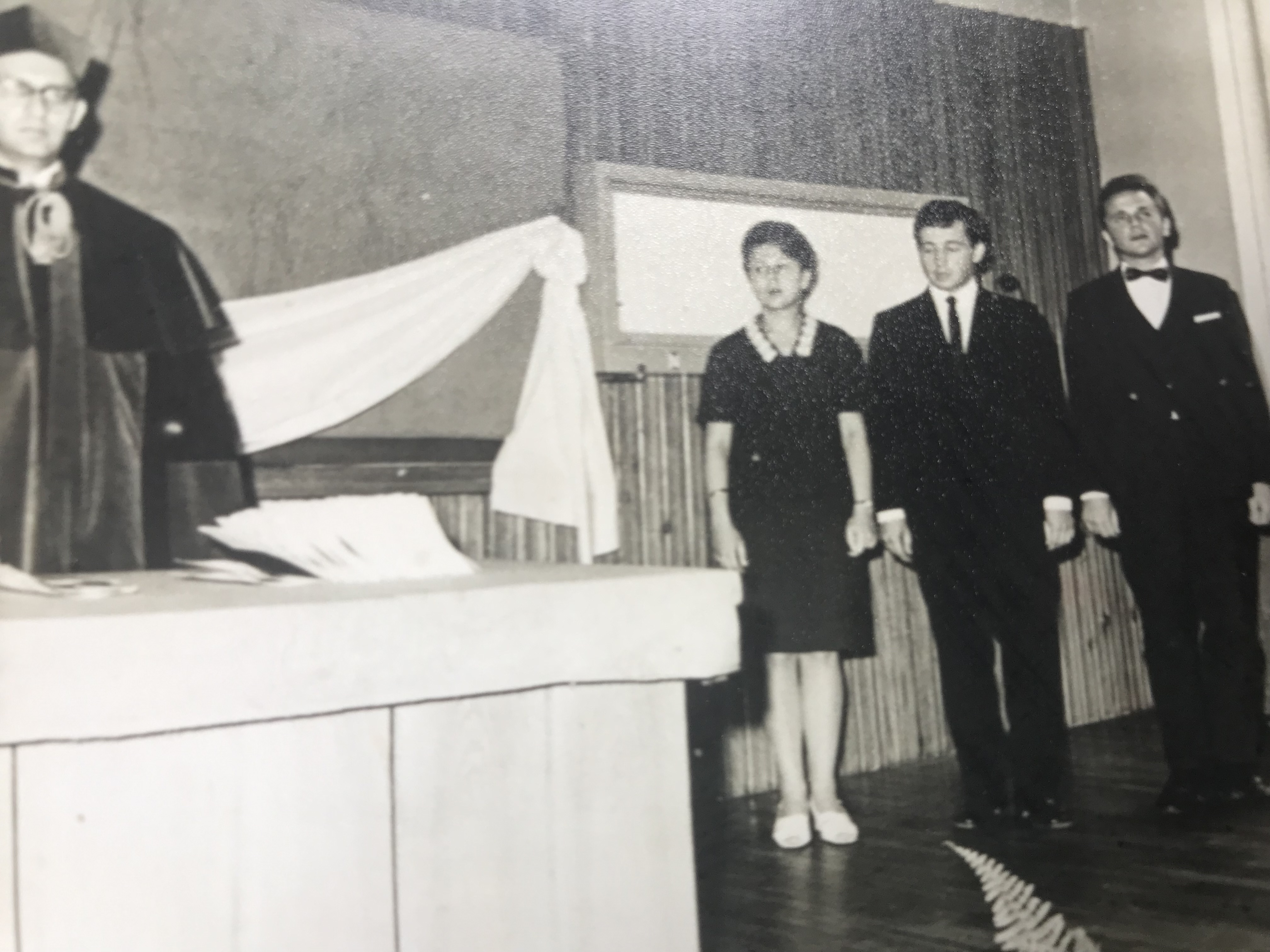 Na czaPo lewej mężczyzna w todze za stłem, po prawej stoją kobieta i dw&oacute;ch mężczyzn. 